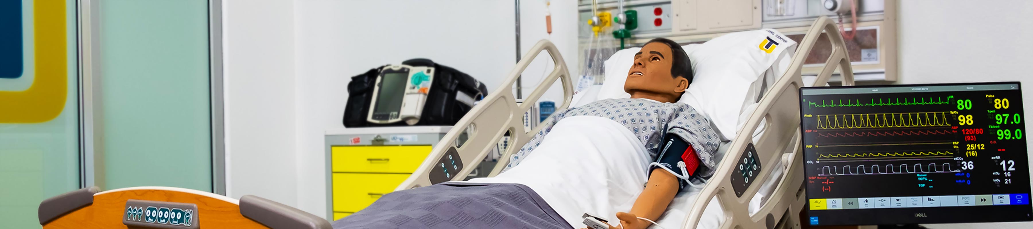 A simulation mannequin in a hospital bed inside the Tang Simulation Center.