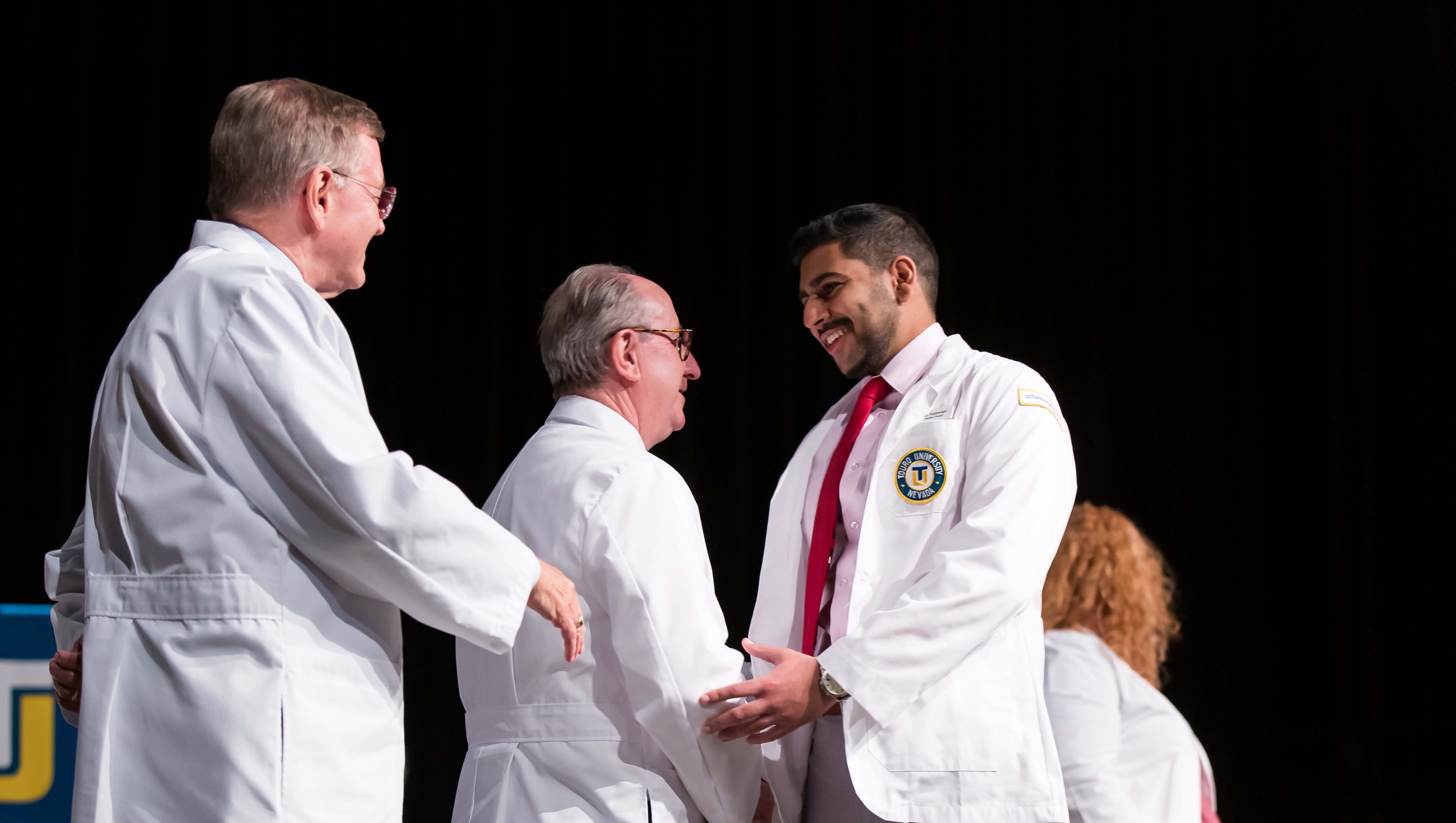 Dr. Wolfgang Gilliar congrats students as they receive their white coats.
