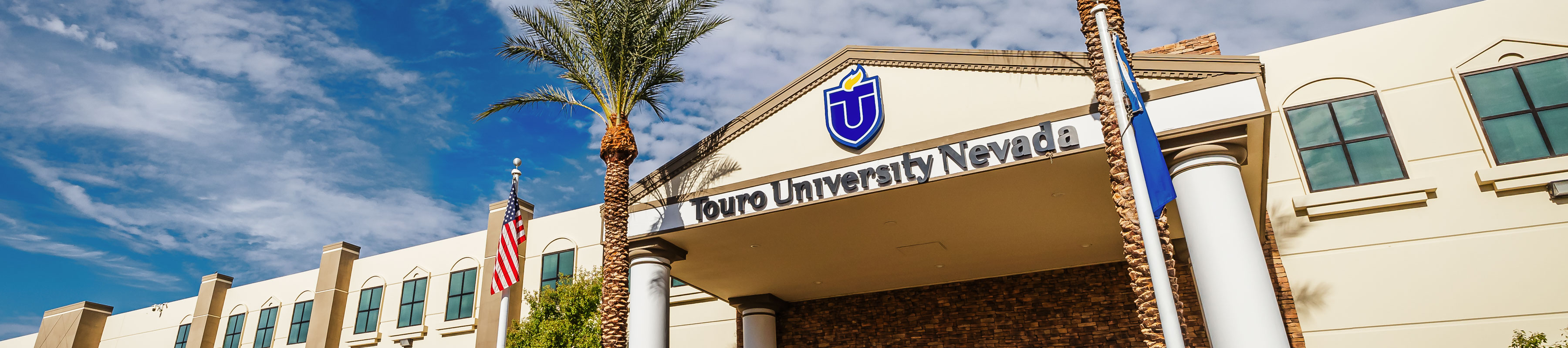 Exterior view of the front entrance of Touro University Nevada building, featuring the university logo