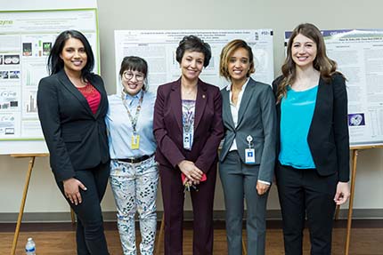 Faculty and student researchers stand in front of of their research posters for a group photo.
