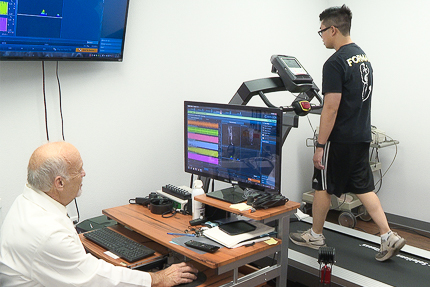 Dr. Laymon examines a student\'s performance and vitals on a treadmill.