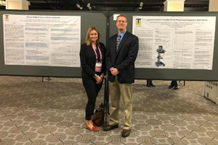 Faculty members standing in front of their research posters.