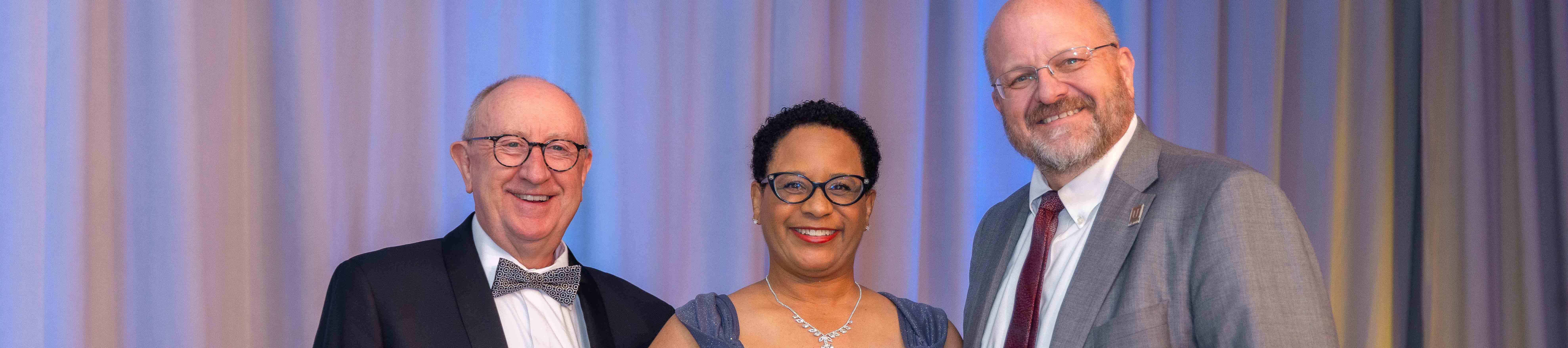 Touro Nevada leadership present an alumni student with an award on stage at a Gala.