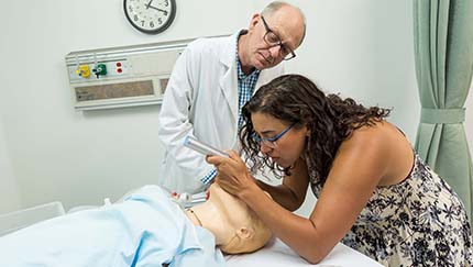 An alumni and a professor in the simulation center.