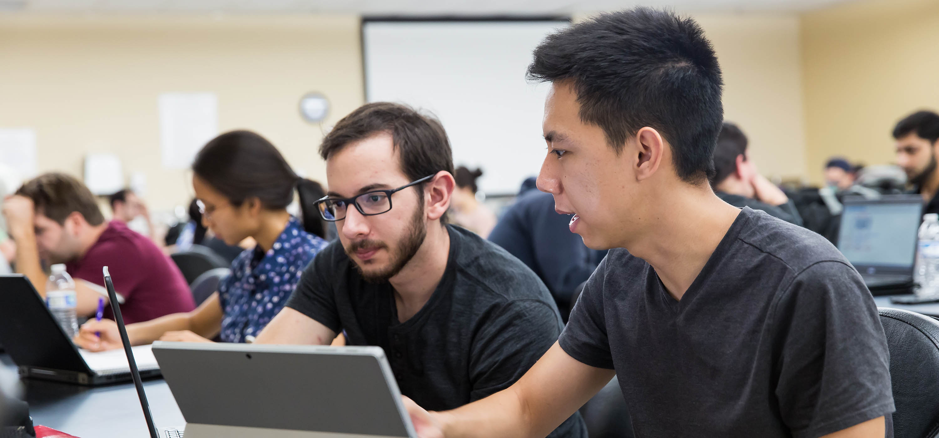 Two students looking at the screen on their laptop computer.