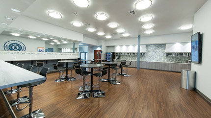 A large bright common space room with table, chairs, counters, and microwaves.
