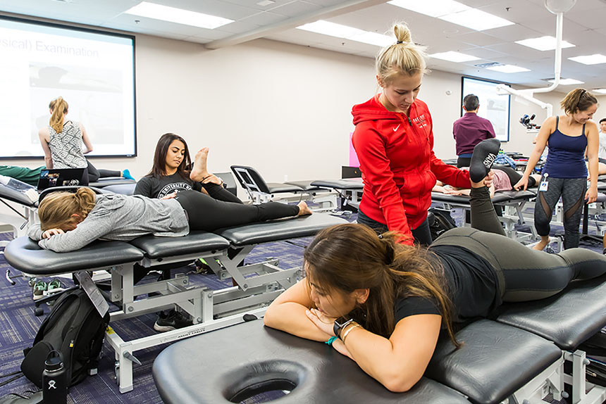 Students practicing physical therapy techniques in a classroom.