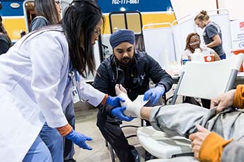 A student wraps a patient's foot. 