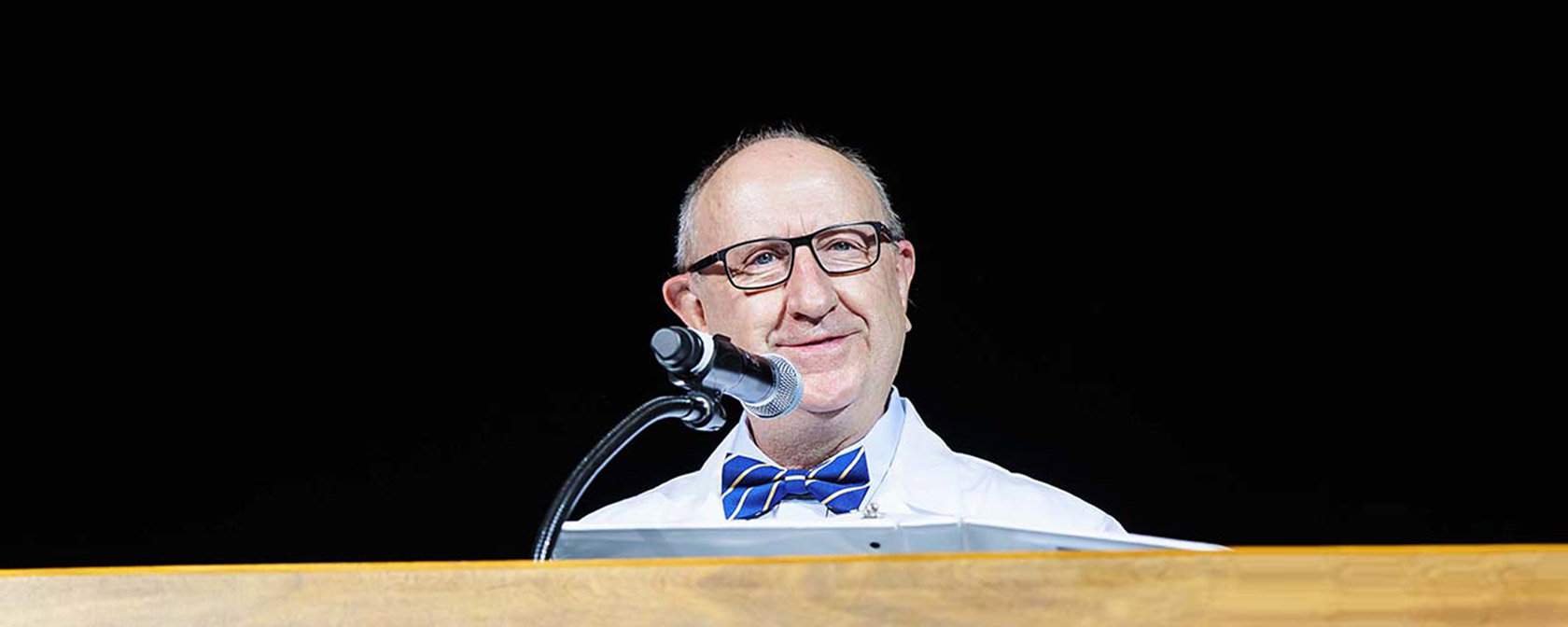 Dr. Gilliar standing on stage at the podium